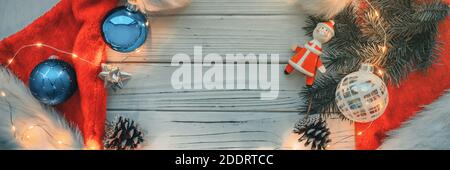 Christmas tree decoration background banner. Copy space on wooden white plank with santa hats, ornaments, balls, santa claus toy panoramic Stock Photo