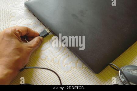 Human hand connecting Computer mouse connection cable plug-in the laptop keyboard. Network connection plugin internet of things and modern wireless te Stock Photo