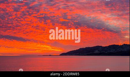 Charmouth, Dorset, UK.  26th November 2020.  A spectacular fiery red sunset fills the sky viewed from Charmouth in Dorset looking towards Lyme Regis at the end of a sunny day   Picture Credit: Graham Hunt/Alamy Live News Stock Photo