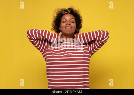 African young woman has a sore neck, isolated on a yellow background. Studio shot Stock Photo