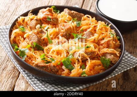 Delicious stewed sauerkraut with pork, onions and paprika close-up in a plate on the table. horizontal Stock Photo