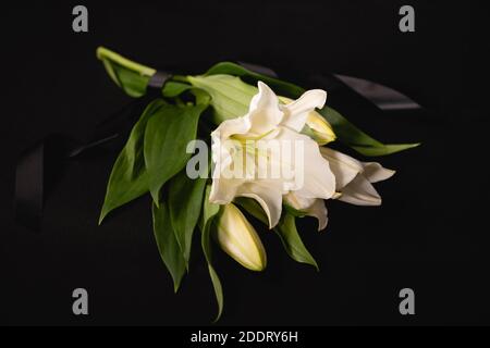 lily bouquet and ribbon on black background, funeral concept Stock Photo