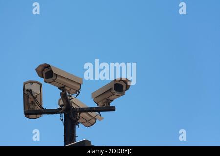 Four security cameras on a pole in the street, from below, with a blue sky. Concepts like security or privacy Stock Photo