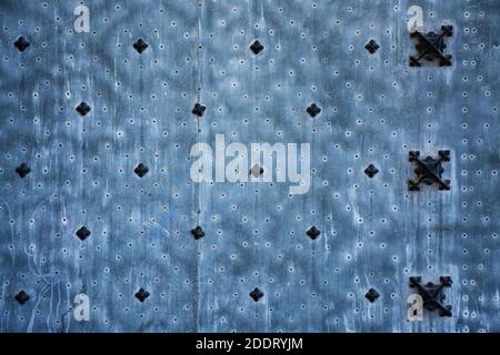 Old metal panel with edging and nails forming patterns, on an old door. Blue background Stock Photo