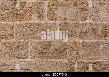 Old textured yellow stone block wall creating a pattern. Background for designs or advertising Stock Photo