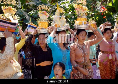 women wearing traditional dresses, carry offers for a funeral, in Bali, Indonesia. Stock Photo