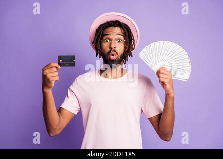 Photo of young african shocked amazed handsome guy male man wear glasses hold credit card dollars isolated on violet color background Stock Photo