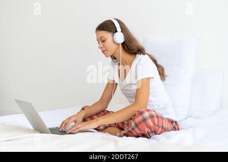 Young woman in headphones studying online, working from home using laptop Stock Photo