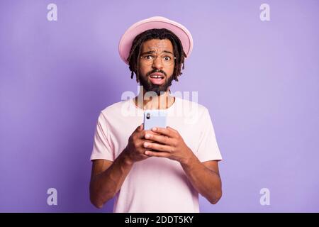 Photo portrait of unhappy man holding phone in two hands isolated on vivid violet colored background Stock Photo