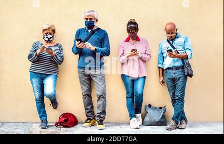 Senior people using mobile smart phone with face mask covered - Retired friends sharing content on smartphone - New normal lifestyle concept Stock Photo