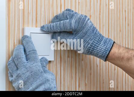 Installation of the wall switch in the room by an electrician, hands in close-up protective gloves Stock Photo