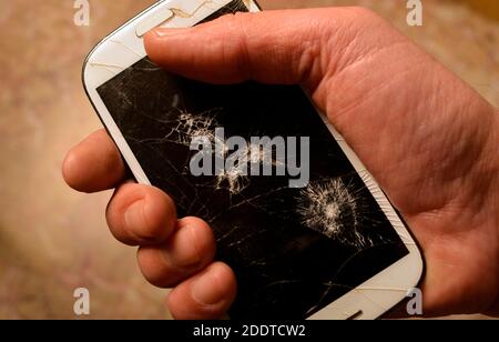 Male hand holding up a smartphone with the broken display. Stock Photo