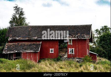 Decaying and abandoned old red barn with holes in the walls and roof. . High quality photo Stock Photo