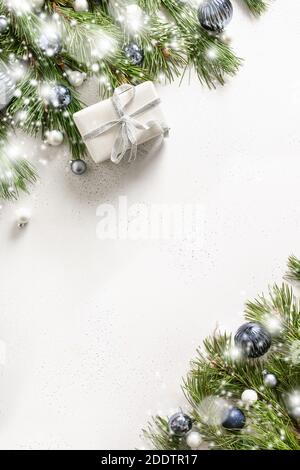 Christmas white frame with gift, fir evergreen branches, blue balls on white background. Xmas vertical greeting card with copy space. Stock Photo
