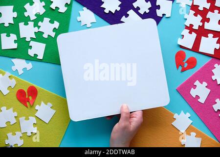 Concept paper design, text space on white page in hand. Jigsaw puzzle elements and multicolor felt. Stock Photo