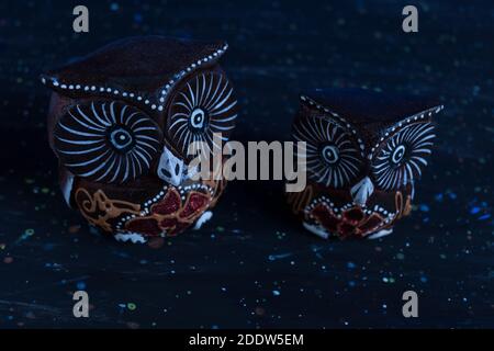 A Figure of a pair of wooden owls on abstract dark background. family concept. Stock Photo