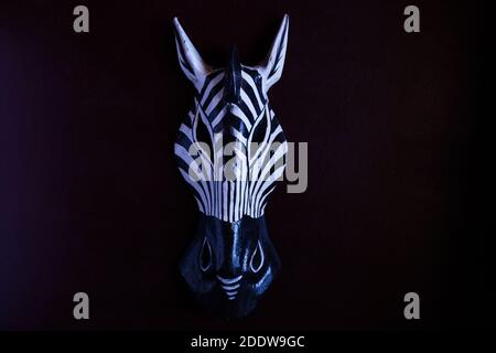 African handmade wooden zebra mask on dark background for wall decoration. Stock Photo