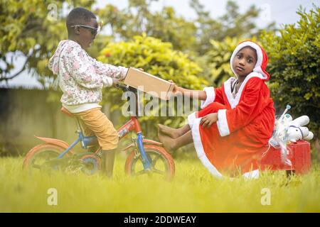 A vibrant shot of two African children playing in garden with Christmas ornaments and clothes Stock Photo