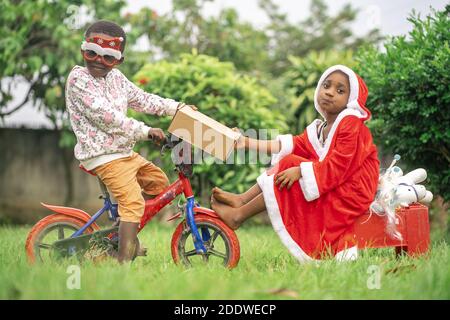 A vibrant shot of two African children playing in garden with Christmas ornaments and clothes Stock Photo