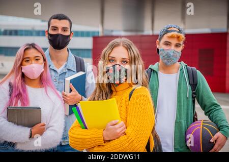 Group of teenagers or students wearing face protective medical masks for protection from virus disease with backpacks walking and talking outdoors Stock Photo