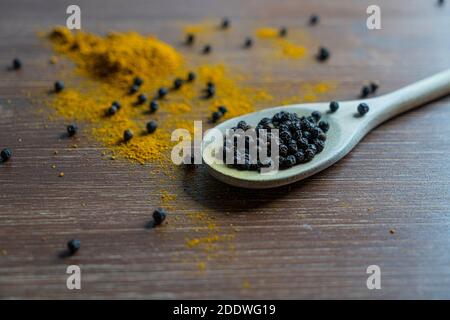 a wooden ladle with curry powder and pepper grain Stock Photo