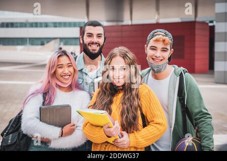 Group of teenagers or students wearing face protective medical masks for protection from virus disease with backpacks walking and talking outdoors Stock Photo