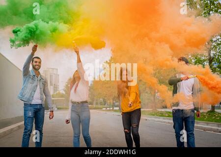 Beautiful Young Man And Woman Hold Light Up Colored Smoke Bombs