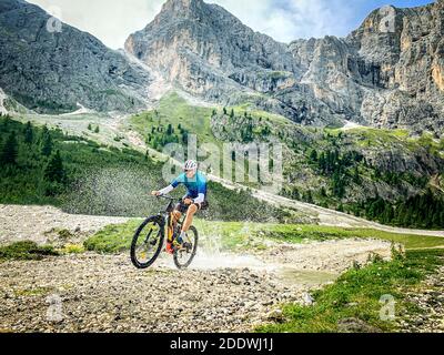 Man doing mountain biking in a mountain route - Sport Man riding a mountain bike passes in through a shallow stream running through tranquil nature Stock Photo