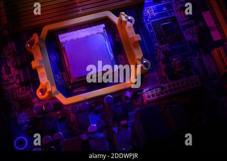 Macro close-up of a microchip, processor, printed circuit Board, or computer motherboard with components: neon colors. The Concept Of Security Of Cybersecurity. Stock Photo