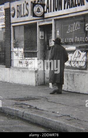 Fine 1970s vintage black and white photography of a regular guy on a city sidewalk in front of Bill's Recreation Parlor in Detroit, Michigan. Stock Photo