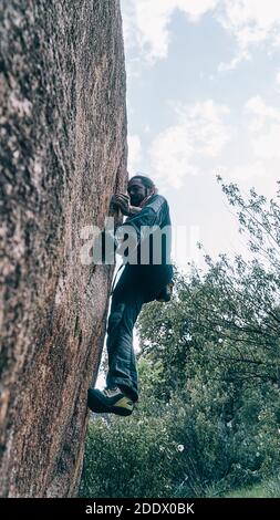 Bottom view of strong man doing rock climbing in a mountain. Stock Photo