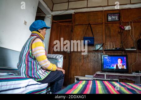 (201127) -- KUNMING, Nov. 27, 2020 (Xinhua) -- Dulong resident Dang Na watches TV at home in Dulongjiang Township of Gongshan Dulong and Nu Autonomous County, southwest China's Yunnan Province, Nov. 1, 2020. Dulong is a mountain-dwelling ethnic group in southwest China. It is one of the least populous of China's 56 minority nationalities. It is also called a 'direct-transition' minority ethnic group because the Dulong people didn't bid farewell to primitive life until the founding of the People's Republic of China in 1949 and since then they directly stepped into the socialist society. Mos Stock Photo