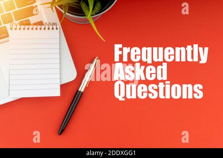 FREQUENTLY ASK QUESTIONS or FAQ text with notepad, laptop, fountain pen and decorative plant on red background. Business and Copy Space Concept Stock Photo