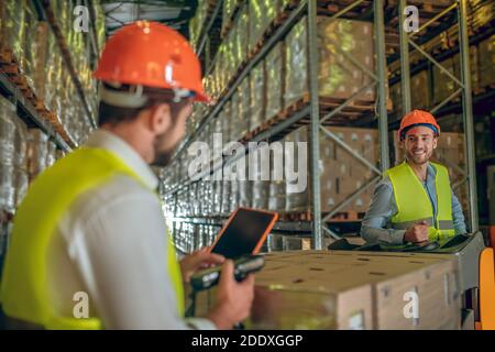 Two warehouse workers in helmets talking while working Stock Photo
