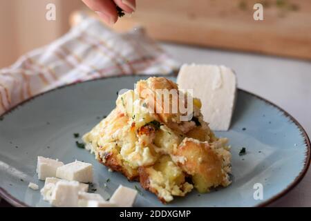 Potato gnocchi, Italian potato dumplings with cheese sauce, ham and basil on a plate/ Chef adding herbs and spices over dish Stock Photo