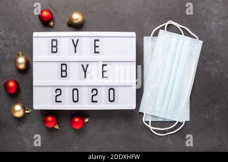 Lightbox with text BYE BYE 2020 with medical mask on dark background. Top view. New year celebration. Happy New Year 2021 concepts - Image Stock Photo