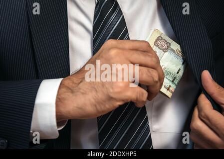 Businessman keeping the United Arab Emirates banknote money in his suit pocket - corruption concept Stock Photo