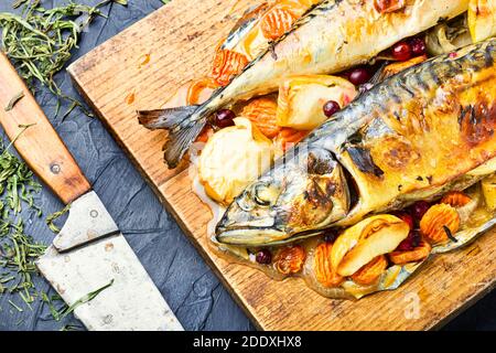 Delicious mackerel fish baked with apples,served on a kitchen board. Stock Photo
