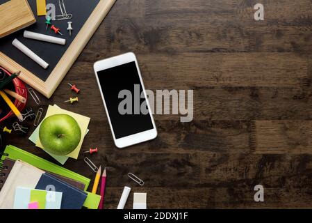 Stationery, education supplies and learning equipment including smartphone on dark brown wooden table background, top view border design with copy spa Stock Photo