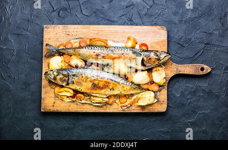Delicious mackerel fish baked with apples,served on a kitchen board. Stock Photo