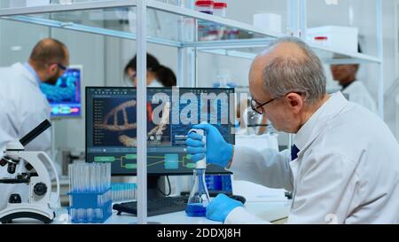 Elderly research scientist using micropipette filling test tubes in ...