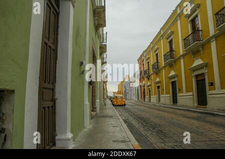 A historic street in Merida, Mexico in the Yucatan Peninsula. The historic buildings are pastel colors and in a colonial architecture style. Stock Photo