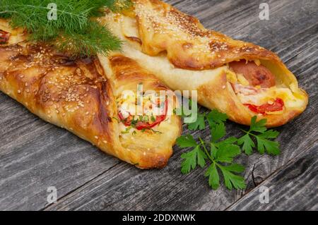Baked sausage in dough with tomatoes, cheese and herbs mini pizza with sauce and sausage. Homemade cakes, handmade snacks. Stock Photo