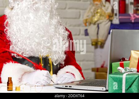 Costumed hands of Santa Claus writing a Christmas letter or greeting on a postcard. close up Stock Photo