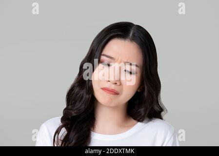Unhappy young Asian woman crying sadly isolated on gray studio background Stock Photo