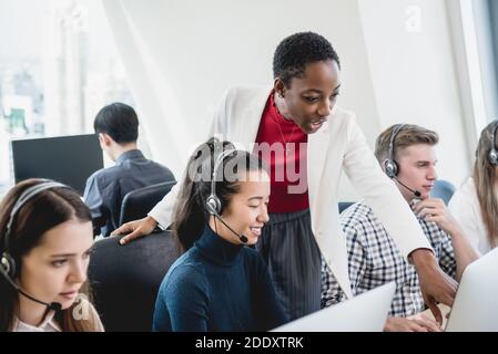 African American female supervisor training work to internatinal team in call center headquarter office Stock Photo