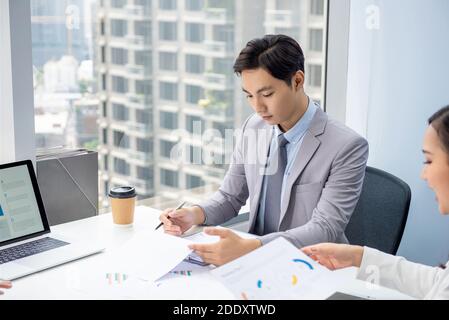 Young Asian businessman concentrating on reading document in the meeting at the office in the city Stock Photo