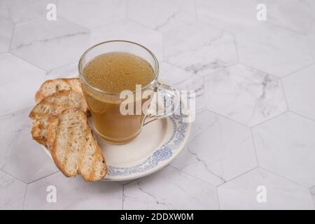 A Cup of hot meat broth for lunch with toasted white bread on a light background. Copy space Stock Photo