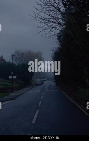 Dark and moody atmospheric rural road on a misty morning in vertical format with copy space Stock Photo