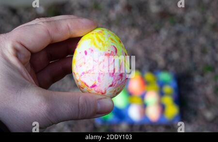 Hand holding up a boiled egg that has been handpainted in different colors - a tradition for Easter holiday in Sweden. Stock Photo
